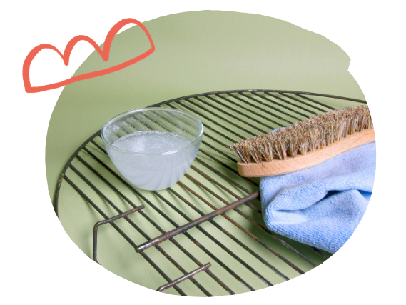 Solution de percarbonate de soude dans un bol, placé sur des grilles de barbecue avec une brosse à récurer et un chiffon - Grand Beau